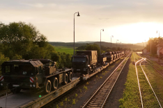 Auf einer Bahnstrecke steht ein Zug aus Flachwagen mit zahlreichen Militärfahrzeugen der Bundeswehr darauf.