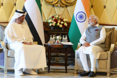 Indian Prime Minister Modi and COP 28 President-elect and Abu Dhabi National Oil Company CEO Al Jaber sit in front of their state flags and chat.