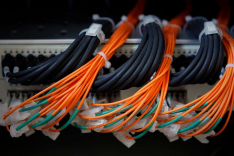 An der Rückseite eines Computers sind zahlreiche Kabelstränge angeschlossen, darunter drei bestehend aus Kabeln mit einer markanten orangeroten Isolierung.