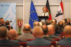 Im Historischen Saal der BAKS steht Bundesverteidigungsministerin Ursula von der Leyen an einem Pult mit dem Bundesadler darauf und spricht vor einem großen Publikum in ein Mikrofon.