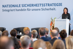 Foto: BAKS/Stollberg Außenministerin Annalena Baerbock steht an einem Redepult und spricht; den Hintergrund bildet eine Wand mit der Aufschrift "Nationale Sicherheitsstrategie"; im Vordergrund sitzen zahlreiche Menschen.