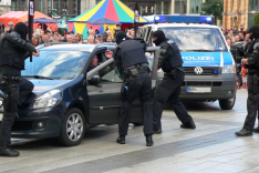 Vermummte und bewaffnete Polizisten  öffnen ein Auto mit einer Person darin