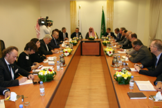 Das Foto zeigt Menschen in arabischer und westlicher Kleidung, die an einem großen Konferenztisch sitzen.