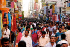 Zahlreiche Menschen drängen sich durch eine überfüllte Marktgasse in Indien