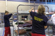 Zwei Mitarbeiterinnen des Katastrophenschutzes Rheinland-Pfalz stellen Betten in einer Notunterkunft auf.
