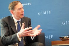 David Petraeus sitzt vor einer Pressewand des German Marshall Fund und spricht unterstützt von Gestik mit einem nicht im Bild befindlichen Gesprächspartner.