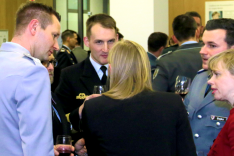 Foto: BAKS/Felten Mehrere Personen in Anzügen und Uniform stehen beieinander und unterhalten sich.