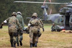 Soldatinnen und Soldaten tragen einen Kameraden zu einem Sanitätshubschrauber