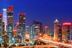 Panoramabild von Pekings „Central Business District“ bei Nacht mit beleuchteten Bürohochhäusern und Außenwerbung