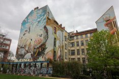 Das Bild zeigt eine bunt bemalte Hausfassade im Berliner Bezirk Neukölln