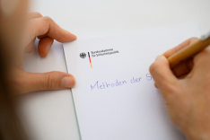 BAKS/Stollberg Eine Person schreibt auf einem Notizblock der BAKS die Worte "Methoden der ..."