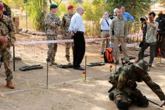 Verteidigungsministerin Ursula von der Leyen besucht die Pionierausbildung des deutschen Einsatzkontingent in Mali; links stehend die Ministerin im Gespräch mit einem deutschen Soldaten, rechts knieend ein malischer Soldat in einem Übungsminenfeld.