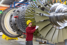 In einer Werkshalle inspiziert ein Mitarbeiter der Siemens AG die Schaufeln einer großen Gasturbine.