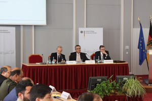 Drei Herren sitzen an einem Tisch und halten einen Vortrag