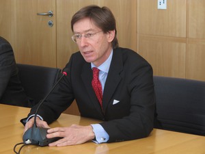 Ein Herr im Anzug sitzt vor einem Mikrophon