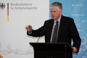 Ein Herr mit dunklem Anzug steht an einem Rednerpult. Ein Herr mit dunklem Anzug steht an einem Rednerpult.