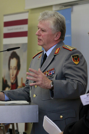 Ein Herr mit grauer Uniform steht an einem Rednerpult