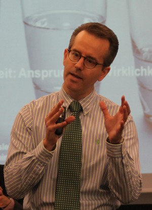 Ein Mann steht gestikulierend vor einer Leinwand