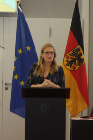 Eine Dame steht an einem Rednerpult und hält eine Rede.