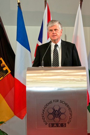 Der Präsident der BAKS, Botschafter Dr. Heumann, steht an einem silbernen Rednerpult.