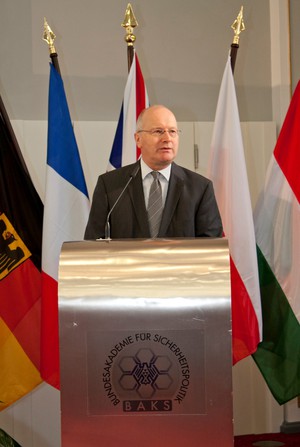 Staatssekretär Fritsche, ein Herr im dunklen Anzug, steht an einem silbernen Rednerpult.
