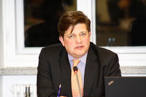 Ein Herr im Anzug sitzt und hält einen Vortrag