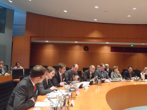 Teilnehmer des Seminars sitzen am halbrunden Tisch im Bundeskanzleramt