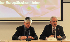 Zwei Herren in Anzügen sitzen an einem Tisch in einer Besprechung.