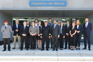 Zahlreiche geschäftlich gekleidete Menschen, darunter drei Uniformträger, stehen vor einem Gebäude mit der Aufschrift "Inspekteur der Marine".