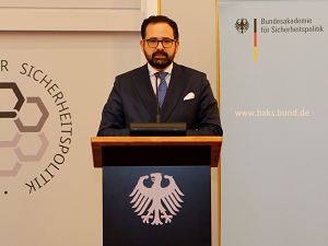 Christian Klein spricht an einem Redepult stehend vor einem Hintergrundaufsteller der BAKS.