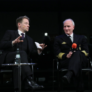 Moderator und Vizeadmiral diskutieren. 