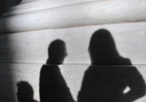 Das Bild zeigt Schatten von Personen vor einer grauen Wand.