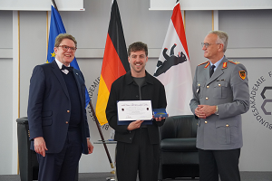 David Matei hält die Urkunde des Karl-Carstens-Preises in den Händen; neben ihm stehen der Freundeskreisvorsitzende Dr. Dirck Ackermann und BAKS-Präsident Generalmajor Wolf-Jürgen Stahl.