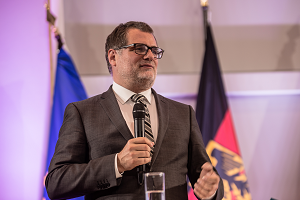 Kanzleramtschef Wolfgang Schmidt steht 2022 vor zwei Fahnen und spricht in eine Mikrofon in seiner Hand.