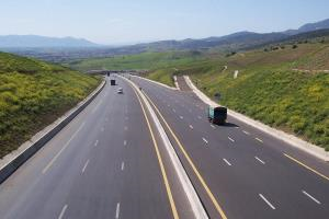 Eine sechsspurige Autobahn führt durch eine steppenartige Landschaft; wenige Autos sind darauf zu sehen..