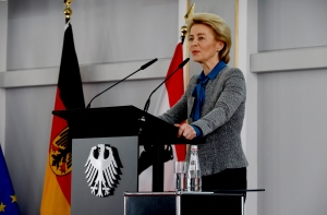 Eine Frau spricht an einem Rednerpult, das ein Bundesadler ziert. Im Hintergrund ist die deutsche Fahne aufgestellt, die Fahnen Europas und Berlins ebenfalls erkennbar.