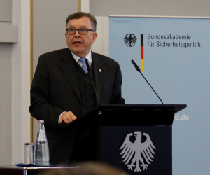 Armin Staigis steht sprechend an einem Rednerpult mit dem Bundesadler darauf; rechts von ihm ragt ein Aufsteller der BAKS auf.