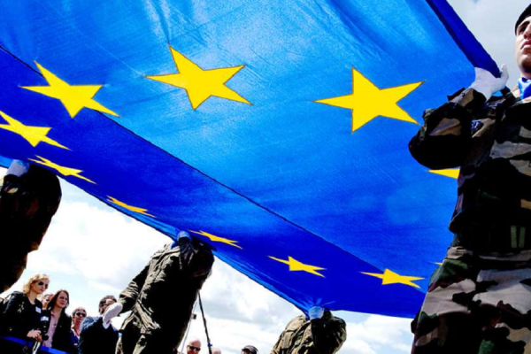 Soldaten unterschiedlicher Nationen halten eine große EU Fahne hoch