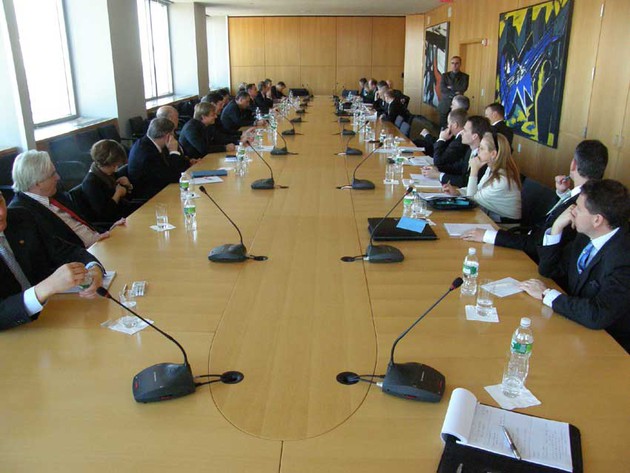 Viele Personen sitzen an einem großen Konferenztisch. Viele Personen sitzen an einem großen Konferenztisch.