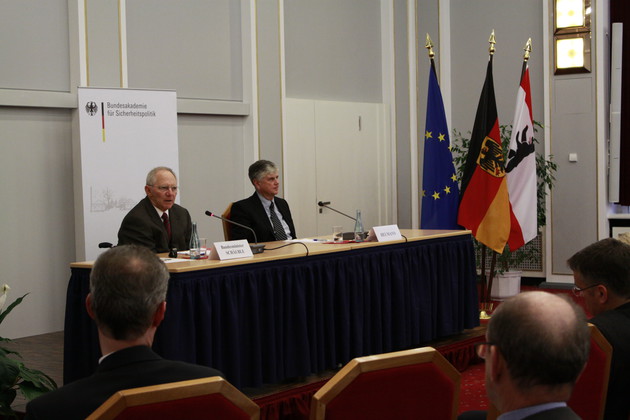 Zwei Herren sitzen an einem Tisch und halten einen Vortrag