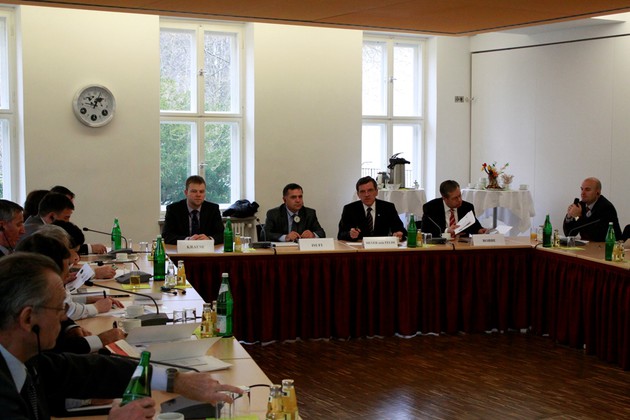 Mehrere Herren in Anzügen sitzen an Tischen