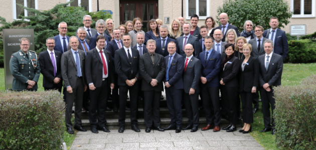 Eine Gruppe geschäftlich gekleideter Menschen, links im Bild ein militäruniformtragender Mann steht vor dem Haus Bonn der BAKS.