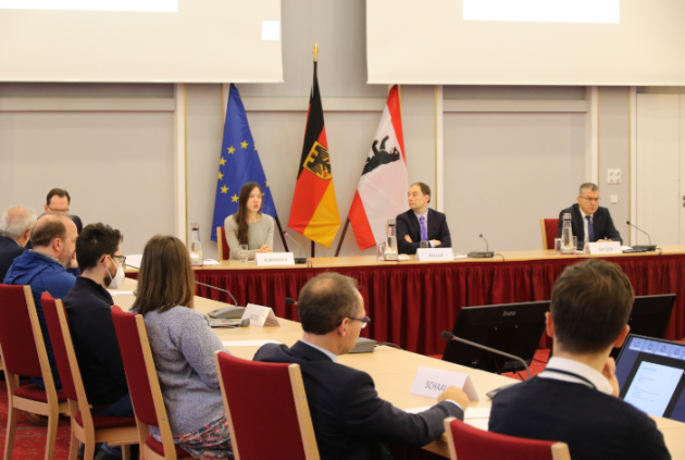 Mehrere Personen sitzen mit Abstand zueinander an einem Konferenztisch