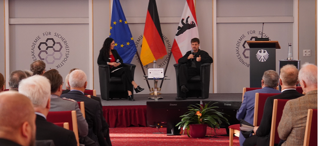 Foto: BAKS Im Historischen Saal der BAKS sitzt David Matei im Gespräch mit Dr. Olga Spaiser vor einem Publikum und spricht in ein Mikrofon.