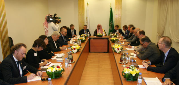 Das Foto zeigt einen Konferenztisch mit Menschen in arabischer und westlicher Kleidung, die an einem großen Konferenztisch sitzen.