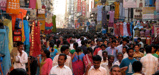 Zahlreiche Menschen drängen sich durch eine überfüllte Marktgasse in Indien