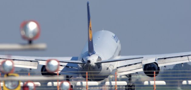 Ein Lufthansa-Jet landet auf einer Landebahn. Im Vordergrund sieht man die Landehilfe.