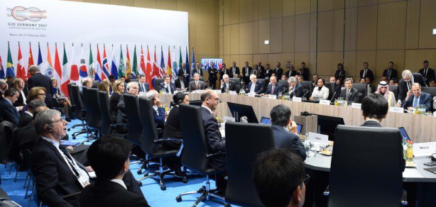 Zahlreiche Minister der G20-Mitgliedsstaaten sitzen um einene großen Konferenztisch vor einer Pressewand mit der Aufschrift "G20 Germany".