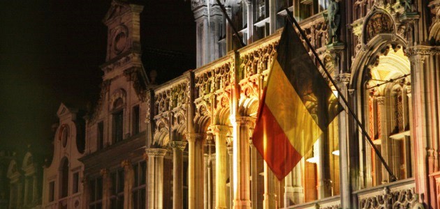 An einer Gebäudefassade weht die Nationalflagge Belgiens