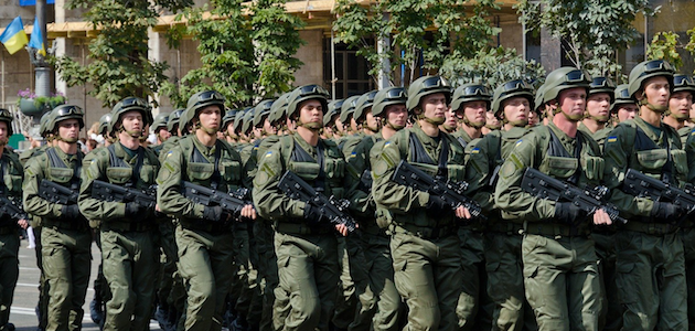 Bewaffnete ukrainische Soldaten marschieren in Formation über eine Straße in Kiew